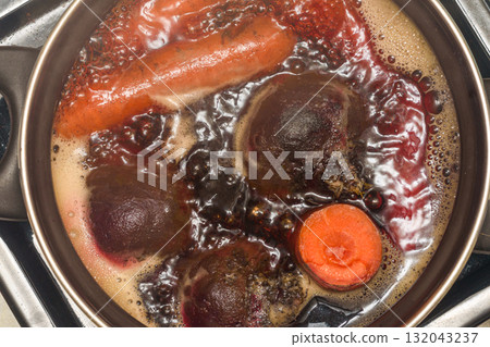 Top view of fresh carrots and beets in a pot of boiling water. 132043237