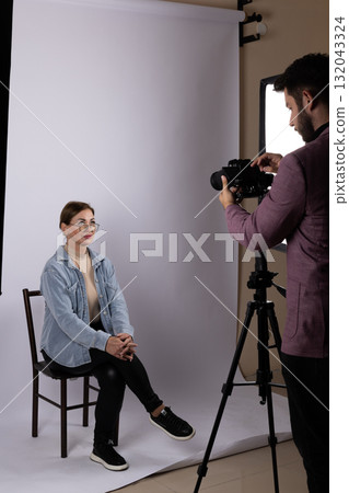 A photographer conducts a photojournalistic interview with a subject in a studio. A photographer conducts a photojournalistic interview with a subject in a studio. 132043324