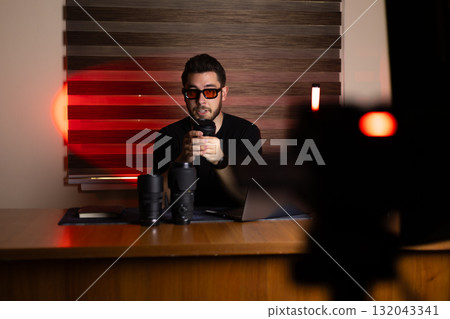 The man is using his laptop to record or edit a podcast 132043341