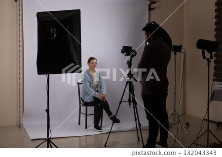 A photojournalist is capturing a portrait of a subject in a studio,  132043343