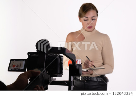A journalist takes notes while being filmed for a news report 132043354