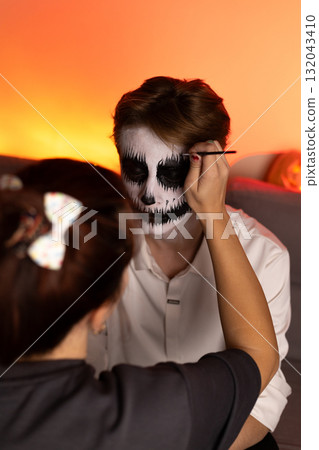 The person in the image is painting a small figurine, possibly a Halloween  132043410