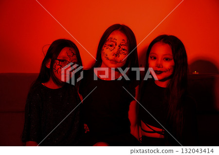 The three girls are posing for a Halloween-themed photo, wearing dark clothes The three girls are posing for a Halloween-themed photo, wearing dark clothes 132043414