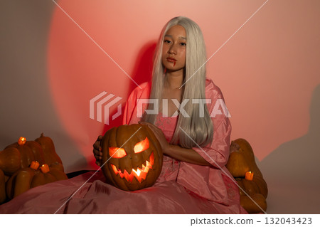 The model is posing with a glowing jack-o'-lantern,embracing the Halloween theme The model is posing with a glowing jack-o'-lantern,embracing the Halloween theme 132043423