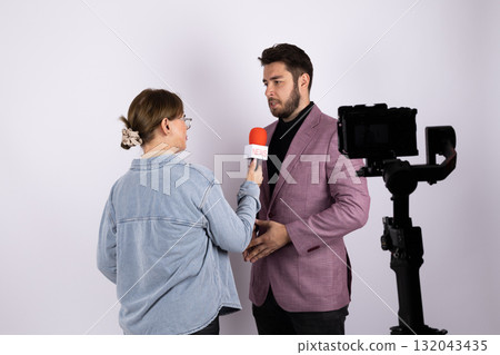 A female journalist is interviewing a man with a microphone and a camera A female journalist is interviewing a man with a microphone and a camera 132043435
