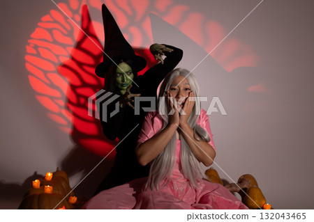 A wicked witch frightens a person dressed in pink with a spooky Halloween A wicked witch frightens a person dressed in pink with a spooky Halloween 132043465
