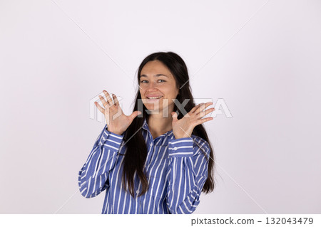 The woman is smiling and holding her hands up with her fingers spread out 132043479