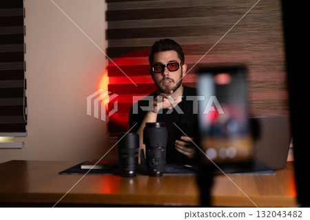 The man is recording a podcast or a broadcast while sitting at a desk  132043482