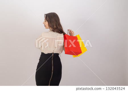 A woman is carrying red and yellow shopping bags over her shoulder 132043524