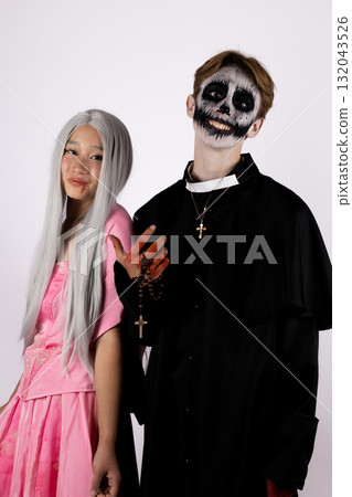 Man and woman dressed as skeletons standing next to a woman holding a pumpkin, 132043526