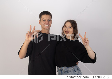 A man and a young woman are standing together, smiling and making a peace sign 132043532