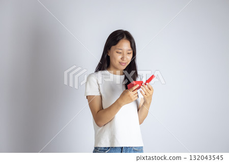 The model is holding a red object and looking down at it 132043545