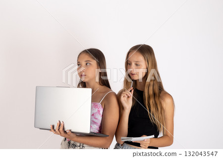 Two young women are looking at something off-camera, with one holding a laptop. Two young women are looking at something off-camera, with one holding a laptop. 132043547