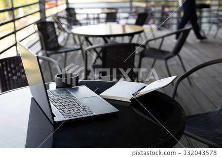 while a laptop and a notebook are on the table. while a laptop and a notebook are on the table. 132043578