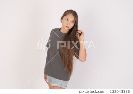The model is standing and touching her long hair with her right hand The model is standing and touching her long hair with her right hand 132043586