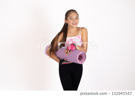 Girl in pink tank top, black leggings, holding yoga mat 132043587