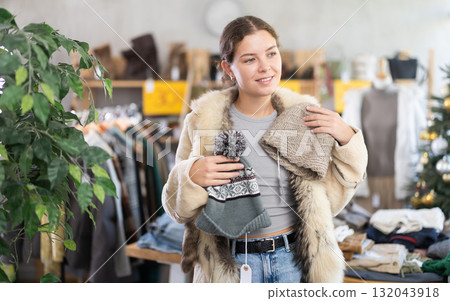 European girl near showcase pick out and buying hat, New Year eve 132043918