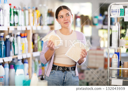 Positive young woman customer buying washcloth in store Positive young woman customer buying washcloth in store 132043939