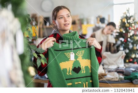 European girl near showcase pick out and buying sweater, New Year eve European girl near showcase pick out and buying sweater, New Year eve 132043941