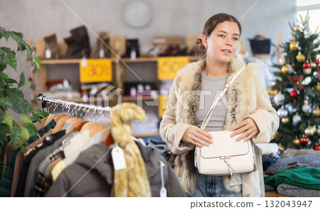 Happy young girl choosing handbag in clothing store 132043947