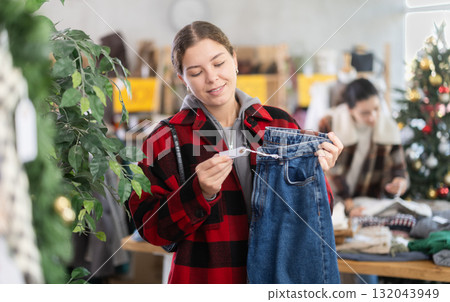 European girl near showcase pick out and buying jeans, New Year eve 132043949