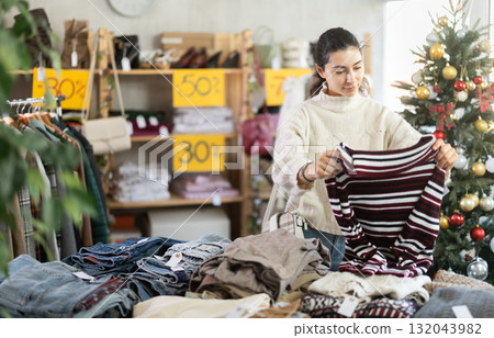 Armenian girl near showcase pick out and buying sweater, New Year eve Armenian girl near showcase pick out and buying sweater, New Year eve 132043982
