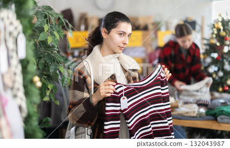 Armenian girl near showcase pick out and buying sweater, New Year eve Armenian girl near showcase pick out and buying sweater, New Year eve 132043987
