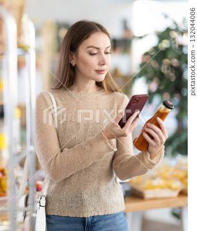 Young woman scanning qr code for chili sauce Young woman scanning qr code for chili sauce 132044006
