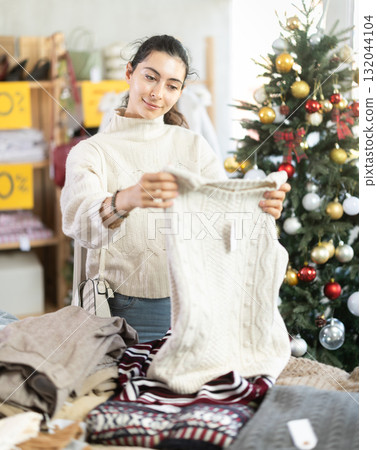 Armenian girl near showcase pick out and buying sweater, New Year eve Armenian girl near showcase pick out and buying sweater, New Year eve 132044104