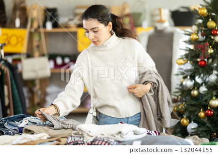 Armenian girl near showcase pick out and buying trousers, New Year eve 132044155