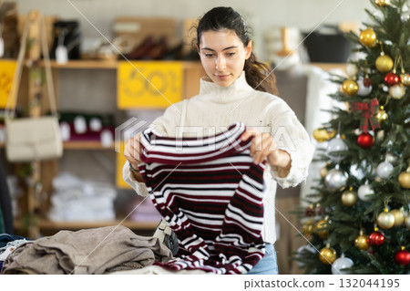 Armenian girl near showcase pick out and buying sweater, New Year eve Armenian girl near showcase pick out and buying sweater, New Year eve 132044195