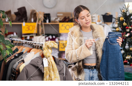 European girl near showcase pick out and buying jeans, New Year eve 132044211