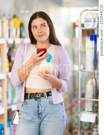 Checking expiration date of liquid hand soap - female shopper scans QR code on label of liquid hand soap using smartphone 132044235