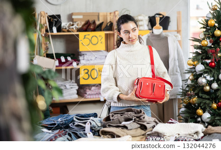 Armenian woman stands in a shop decorated for Christmas and chooses a handbag Armenian woman stands in a shop decorated for Christmas and chooses a handbag 132044276