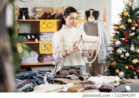 Armenian girl near showcase pick out and buying handbag, New Year eve 132044297