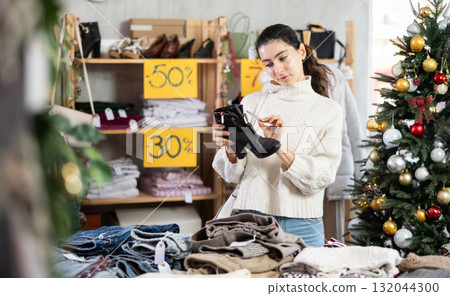 Selective young Armenian girl choosing heeled ankle boots in clothing store 132044300