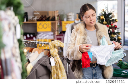 Young girl near showcase pick out and buying ladys panties, New Year eve Young girl near showcase pick out and buying ladys panties, New Year eve 132044331