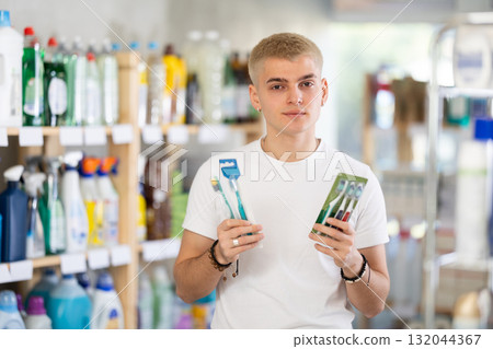 Portrait young man choosing best toothbrush in supermarket Portrait young man choosing best toothbrush in supermarket 132044367