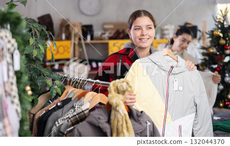 Woman choosing a down jacket in a Christmas shop Woman choosing a down jacket in a Christmas shop 132044370