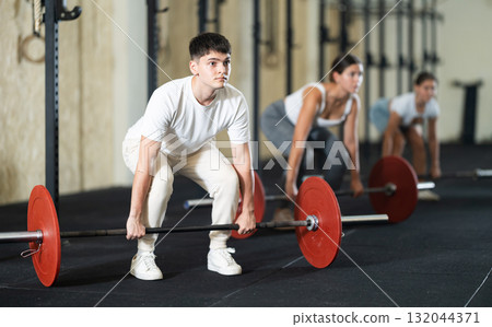 Young guy lifts barbell in gym Young guy lifts barbell in gym 132044371