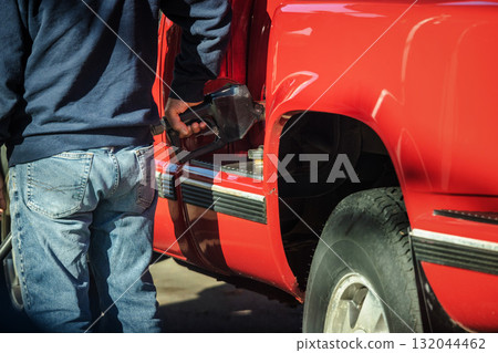 Man refueling red pickup truck at gas station in the United States Man refueling red pickup truck at gas station in the United States 132044462