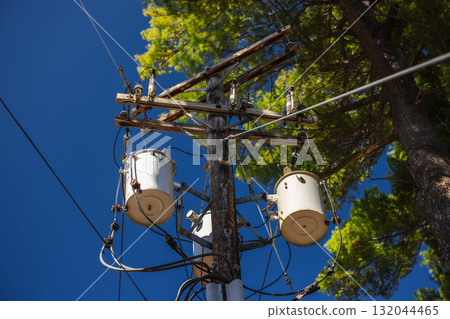 Wooden utility pole with power transformers and electrical cables against blue sky in the United States 132044465