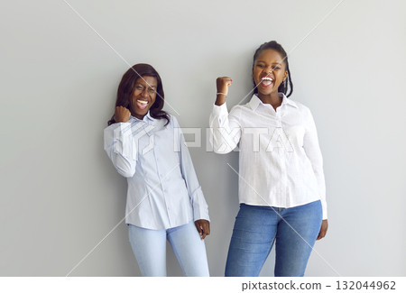Positive African American Women Celebrating Success on Grey Background Positive African American Women Celebrating Success on Grey Background 132044962