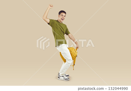 Cheerful funny guy student with school backpack having fun on beige studio background. 132044990