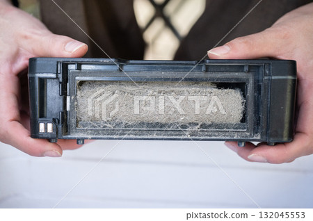 Woman holding a vacuum dust filter for cleaning it. Woman holding a vacuum dust filter for cleaning it. 132045553