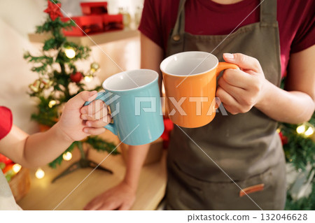 Holiday Cheer. Family bonding over hot cocoa in colorful mugs during Christmas celebration. Holiday Cheer. Family bonding over hot cocoa in colorful mugs during Christmas celebration. 132046628