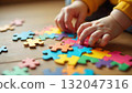 A child's hand is placed on a puzzle piece, highlighting creativity and happiness on International Children's Day 132047316