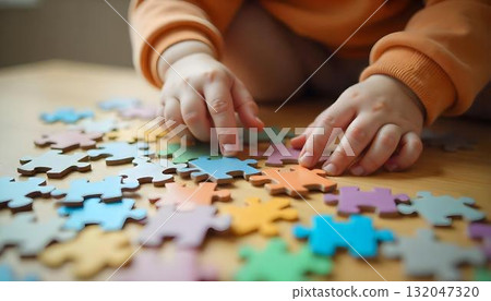 A child's hand touches a colorful puzzle piece, symbolizing creativity and joy on International Children's Day 132047320