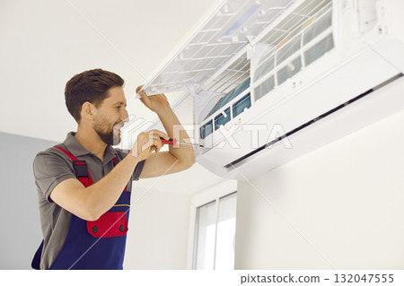 Technician man in uniform installing, repairing air conditioner 132047555