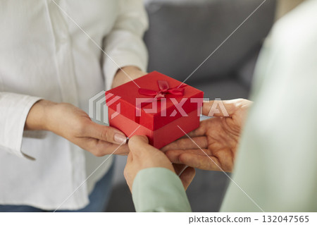 Two people, male and female hands hold gift box with red ribbon. Two people, male and female hands hold gift box with red ribbon. 132047565